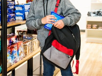 an-eleven-year-old-child-stealing-cookies-in-store-he-is-sliding-a-bag-of-cookies-or-treats-into-his.jpeg