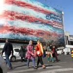 epa12775532-iranians-walk-next-to-a-huge-anti-u-s-billboard-on-a-street-in-tehran-iran-25-february-2.webp