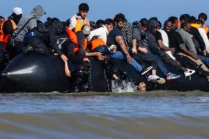 files-migrants-try-to-board-a-smuggler-s-boat-in-an-attempt-to-cross-the-english-channel-off-the-bea.webp