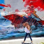 a-woman-walks-past-an-anti-us-and-anti-israel-mural-depicting-missiles-hitting-an-aircraft-carrier-i.jpeg