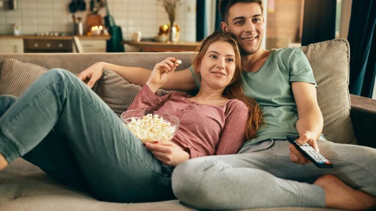 pareja-sonriente-comiendo-palomitas-maiz-viendo-television-mientras-relaja-sofa.jpeg